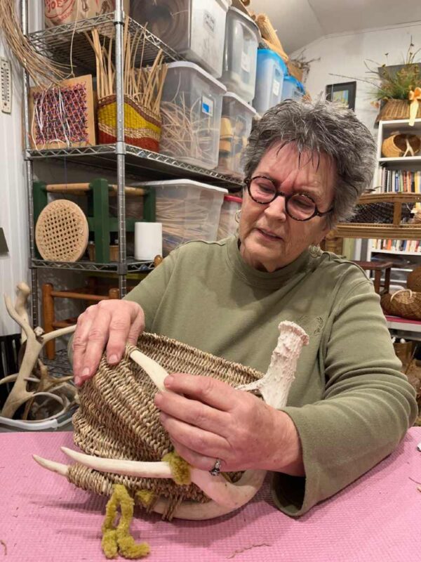 Cathryn Peters weaving an antler basket sculpture in her wicker weaving studio, Hudson, WI.