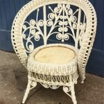 White painted Victorian Heywood-Wakefield ladies chair heavily embellished with wooden beads along the swooping arm and back. Curlicues throughout the back and apron.