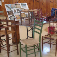 Wicker chairs around a glass table with a collage on it
