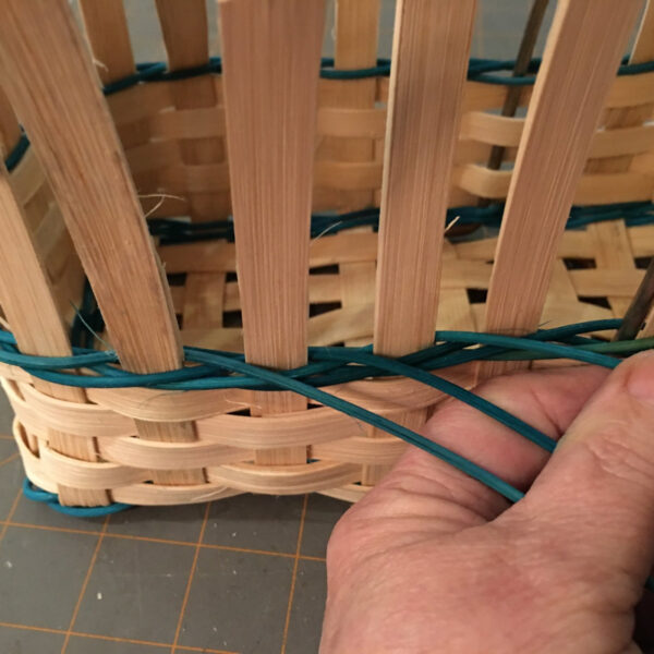 A hand weaving a basket