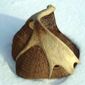 Moose antler basket sculpture by Cathryn Peters sitting in the snow.