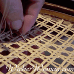 Detail close-up picture of a person's hand weaving hole to hole traditional chair caning in process.