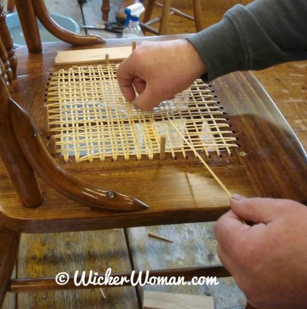 Strand chair cane weaving-pulling through the cane in the right direction. 